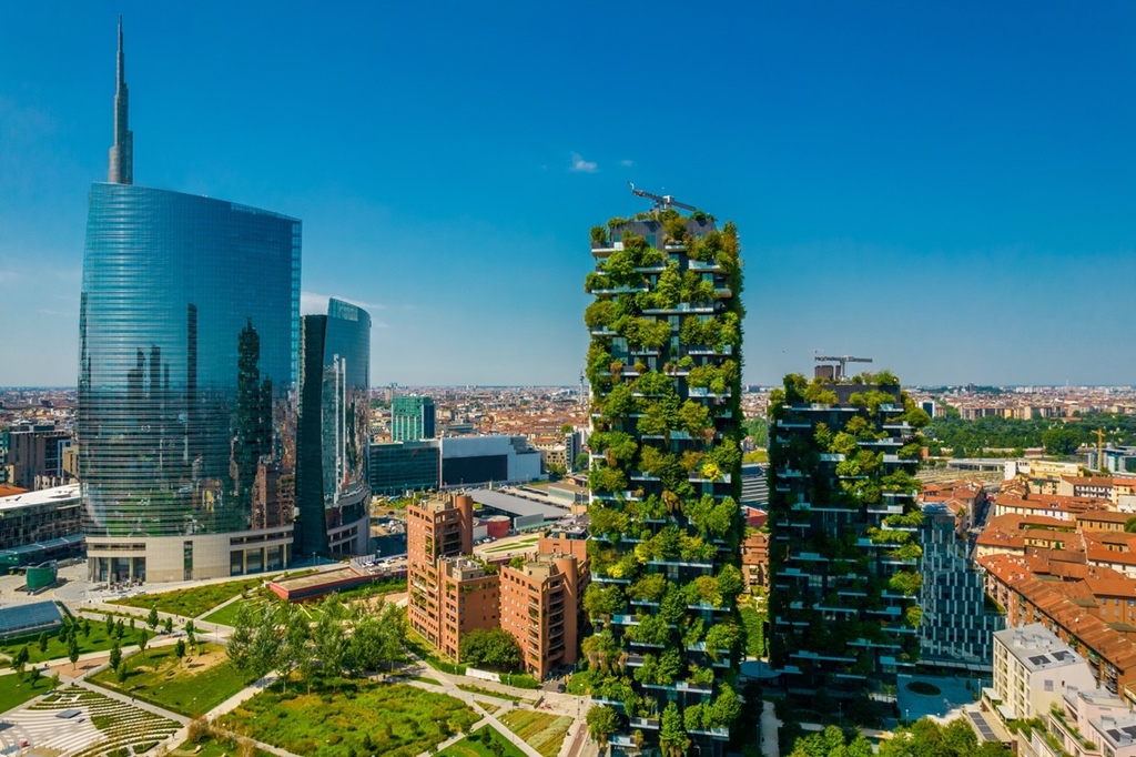 Tall modern cityscape with glass skyscrapers and vertical gardens on high-rise buildings.